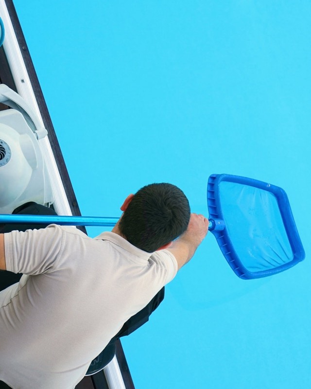 Profissional realizando aspiração e limpeza de piscina